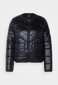Veste matelassée noire avec fermeture éclair devant, deux poches avant, manches longues et encolure ronde sans col, marquée d'une étiquette orange « BOSS » à l'intérieur.