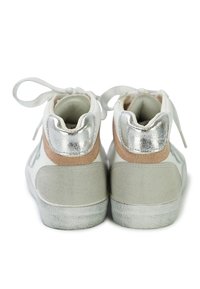 White high-top sneakers featuring a silver back panel, beige suede accents, and textured gray soles. Laces tied at the front.