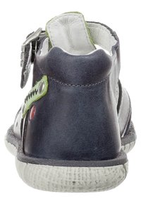 Laivastonsininen nahkasandaali, jossa vihreä yksityiskohta ja punaiset metalliosat. Varustettu kuvioidulla pohjalla ja avoimella takakannalla, jossa säädettävä hihna.