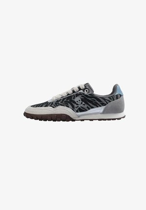 Sneakers with a black and gray zebra pattern, suede and mesh material, silver skull detail, white and gray accents, and brown rubber sole.