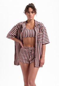 Gestreiftes Loungewear-Set mit einem geknöpften Hemd, einem Cropped-Top und Shorts in Rot, Marineblau und Weiß. Weicher Stoff und lockere Passform.