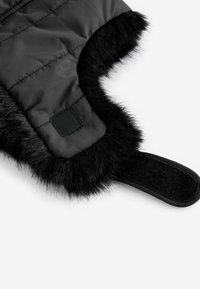 Mitaine noire rembourrée avec une douce bordure en fausse fourrure, présentant une surface texturée et une bande velcro pour une fermeture sécurisée.