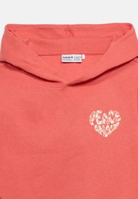 Κοραλλιογενές ροζ φούτερ με κουκούλα, με μια καρδιά σχήματος "Peace Amour" σε άσπρο και μια ορατή ετικέτα ρούχου μέσα στο γιακά.