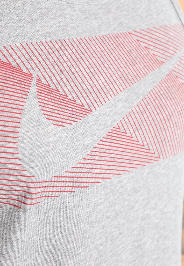 Graues Baumwoll-T-Shirt mit einem roten Nike-Logo, das diagonale Linien auf der Vorderseite bildet. Rundhalsausschnitt, kurze Ärmel.