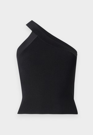 Musta ribattoppi yhdellä olalla, laivastonsiniset pleated-shortsit ja kudottu ruskea laukku. Mallilla on päällään mustat nilkkasukat ja ballerinat.
