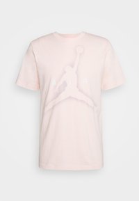 Camiseta de algodón rosa claro con mangas cortas. Presenta un gran gráfico blanco de una silueta en salto y la palabra "AIR" en letras mayúsculas.