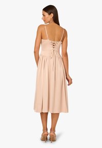 Blassrosa, ärmelloses Midikleid mit einem geschnürten Rücken, plissiertem Rock und dünnen Trägern, aus einem glatten, leichten Stoff gefertigt.