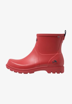 Botte en caoutchouc imperméable rouge jusqu'à la cheville avec semelle texturée, languette au talon et petit logo latéral, vue de profil gauche sur fond blanc.
