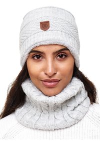Gray knitted beanie and neck warmer set with a textured cable pattern and a leather logo patch. Soft, cozy material provides warmth.