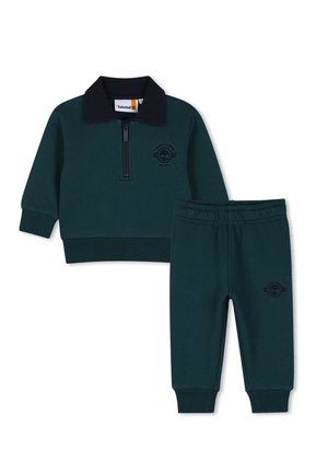 Tenue pour tout-petit vert foncé avec haut zippé à manches longues, col noir, et pantalon assorti à taille élastique, tous deux avec logos Timberland.