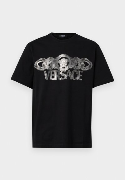 T-shirt en coton noir avec un logo argenté de Versace, présentant un médaillon de lion et un design en chaîne sur le devant. Style classique à col rond.