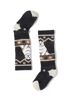 Calcetines oscuros con dedos y talones beige que presentan un patrón de perro sonriente con copos de nieve, huellas de patas y formas geométricas.