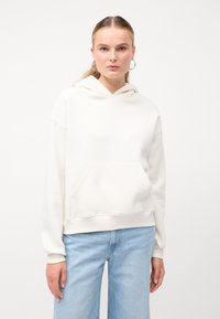Felpa crema con tasca frontale, vestibilità comoda, polsini e orlo a costine. Abbinata a jeans a gamba larga blu chiaro. Design semplice e minimalista.