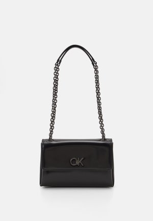 Black leather handbag with a chain strap, featuring a CK logo on the front, displayed against a white background.