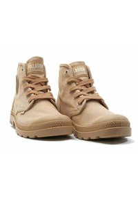 Scarpe alte in tela beige con suole in gomma, punte arrotondate, otto occhielli e lacci tonalità. Presentano il marchio sulla linguetta e sul lato.