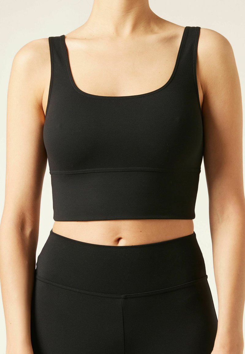 Top de tirantes corto negro con un escote amplio y tirantes gruesos, fabricado con un material elástico, que presenta una textura suave y costuras mínimas.