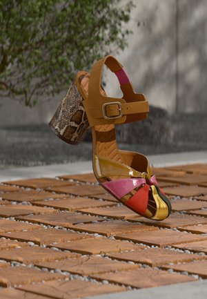 Χρωματιστό σανδάλι με πολλούς ιμάντες, που διαθέτει τακούνι μουσταρδί με λεπτομέρεια φιδιού, και ολοκληρώνεται με γυαλιστερές ροζ, χρυσές και πράσινες πινελιές.
