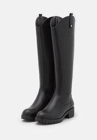 Knee-high black faux leather boots with a rounded toe, block heel, and scalloped top. Features a textured rubber sole for traction.