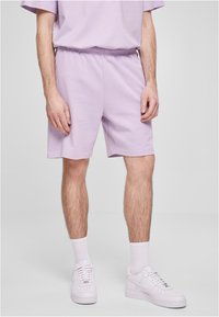 Lilla bomullsshorts med elastisk midjebånd, kombinert med hvite sneakers. Stoffet er glatt, gir en avslappet passform og et uformelt design.