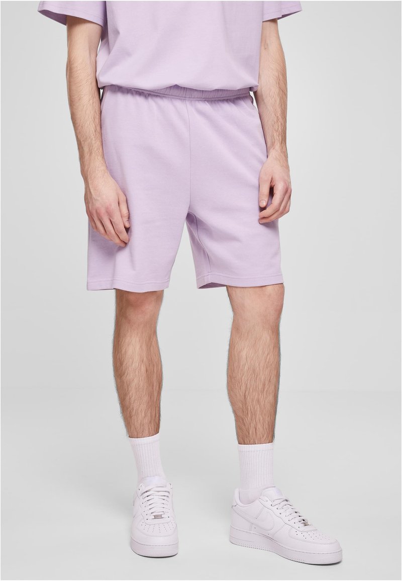 Lilla bomullsshorts med elastisk midjebånd, kombinert med hvite sneakers. Stoffet er glatt, gir en avslappet passform og et uformelt design.