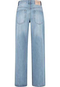 Light blue straight-leg jeans with back pockets and a leather brand patch on the waistband reading "2Y STUDIOS."