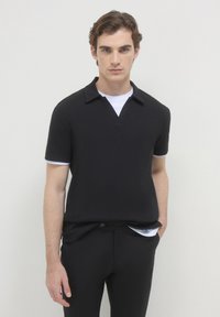 Polo nero a maniche corte con superficie texture, colletto e dettagli bianchi a contrasto sulle maniche. Design slim fit.