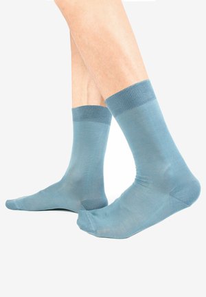 Blaue Baumwollsocken mit einem gerippten Bündchen, glatter Textur und mittellanger Länge, die eine einfarbige Darstellung ohne Muster oder zusätzliche Akzente zeigen.