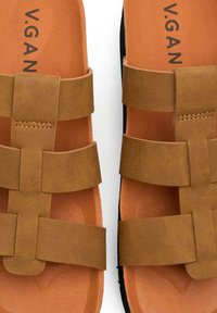 Brown vegan leather sandals with wide straps and a textured finish; padded insole; black rubber sole, embossed brand logo on the footbed.