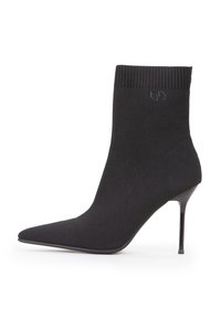 Czarne botki za kostkę z dzianinowym cholewką, spiczastym noskiem i obcasem w szpilce. Oferują prążkowany mankiet oraz subtelny detal z logo.