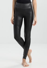 Svarte, blanke tights med høy midje, laget av et glatt, elastisk materiale, med en lett glans og en tettsittende silhuett.