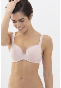 Vaaleanpunainen liivi, joka on valmistettu sileästä kankaasta ja jossa on pitsiyksityiskohtia kupissa ja hihnoissa, keskellä on pieni solmu.