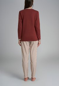 Top a maniche lunghe color bordeaux con pantaloni da pigiama a fantasia crema e marrone, caratterizzati da un design a griglia e una cintura elastica per il massimo comfort.
