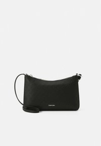 Čierna crossbody taška Calvin Klein s reliéfnym vzorom loga a strieborným zipsom na bielom pozadí.