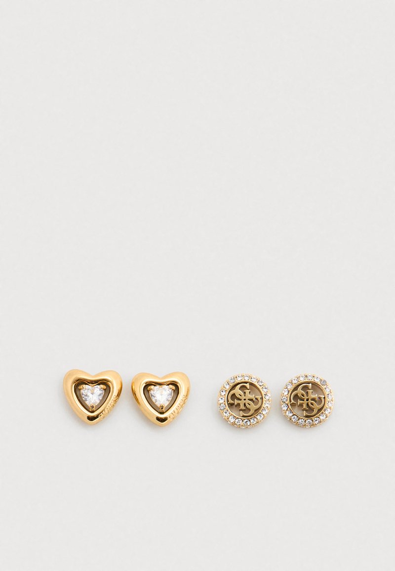 Σκουλαρίκια καρφωτά σε χρυσό τόνο με δύο καρδιές με διαφανείς πέτρες και δύο στρογγυλά σχέδια με λογότυπο περιβάλλεται από διαφανείς κρυστάλλους.