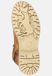 Bota de cuero marrón con una suela de goma beige texturizada que presenta un diseño de unicornio y estrellas, y un perfil pronunciado para mayor tracción.