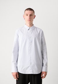 Šviesiai mėlynas dryžuotas mygtukų užsegimo marškiniai su smailiu apykakle, ant priekio išsiuvinėtas tekstas "Calvin Klein" ir ilgomis rankovėmis.