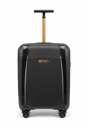 Valise rigide noire à roulettes avec quatre roues et une poignée télescopique dorée prolongée, marquée "EPIC" à l'avant.