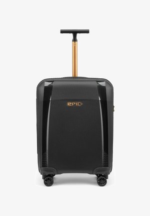 Schwarzer Hartschalen-Trolley mit vier Rollen und ausgezogenem goldfarbenem Teleskopgriff, vorn mit dem Schriftzug "EPIC".