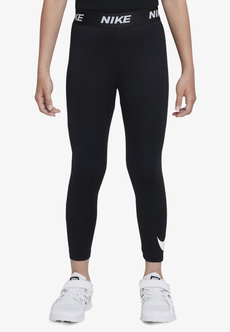 Mustat Nike-legginssit, joissa on leveä vyötärönauha ja valkoinen "NIKE"-teksti. Nilkan lähellä on pieni valkoinen Swoosh-logo. Tasainen kangaspinta.