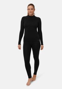 Top a maniche lunghe termico nero e leggings realizzati in materiale morbido e elastico. Design aderente con collo alto e look senza cuciture. Nessun motivo o accessorio.