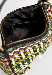 Mała otwarta torebka koralikowa z czarną tkaniną wewnątrz oraz zielonymi, żółtymi, białymi i brązowymi geometrycznymi wzorami z koralików oraz złotym suwakiem.