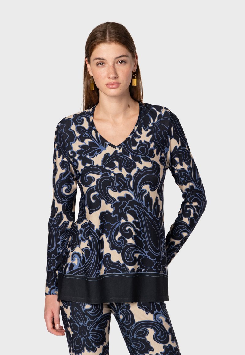 Maglietta a maniche lunghe con scollo a V color crema, caratterizzata da un motivo paisley blu e navy, con orlo nero a tinta unita. Texture morbida.