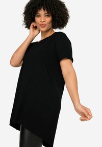T-shirt noir à manches courtes, doté d'un ourlet arrondi et d'une coupe décontractée. Fabriqué dans un matériau doux et texturé.