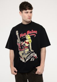 Black oversized t-shirt featuring a graphic design of a blonde woman with a guitar and text "Van Halen" in red, cotton material.