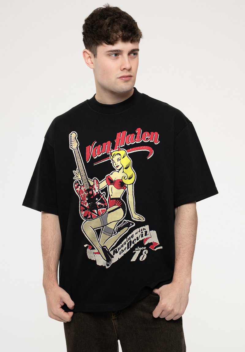 Black oversized t-shirt featuring a graphic design of a blonde woman with a guitar and text "Van Halen" in red, cotton material.