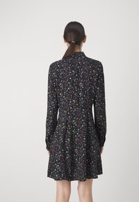Abito nero con maniche lunghe, caratterizzato da una stampa floreale in vari colori. Design a gonna svasata, il tessuto appare leggero e morbido.