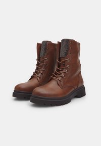 Botas de tobillo de cuero marrón con un cuello texturizado y con patrón, parte delantera con cordones y cremallera lateral. Suela de goma para tracción y durabilidad.