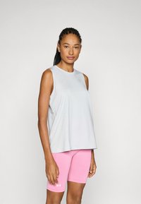 Lys grå ermeløs topp laget av mykt stoff, sammen med rosa tettsittende shorts med hvite logo-detaljer og en glattekstur.