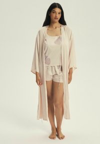 Jasnoróżowy satynowy zestaw do spania, w skład którego wchodzi kimono, top na ramiączkach z kwiatowym wzorem oraz dopasowane szorty z elastycznym pasem.