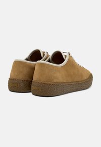 Scarpe in suede marrone con suola in gomma marrone testurizzata. Presentano lacci bianchi e una fodera beige, con il logo "CAMPER" impresso sul tallone.